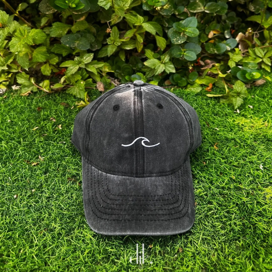 Black cap with a white wave design on grass
