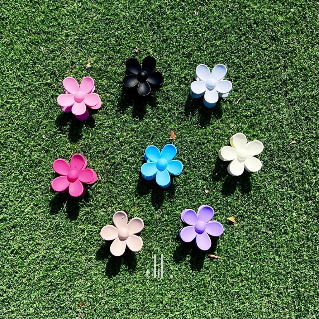 Set of colorful flower-shaped hair clips on a green grass background