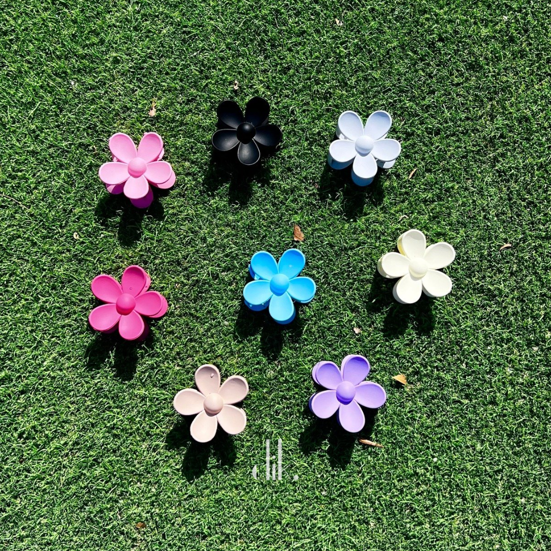 Set of colorful flower-shaped hair clips on a green grass background